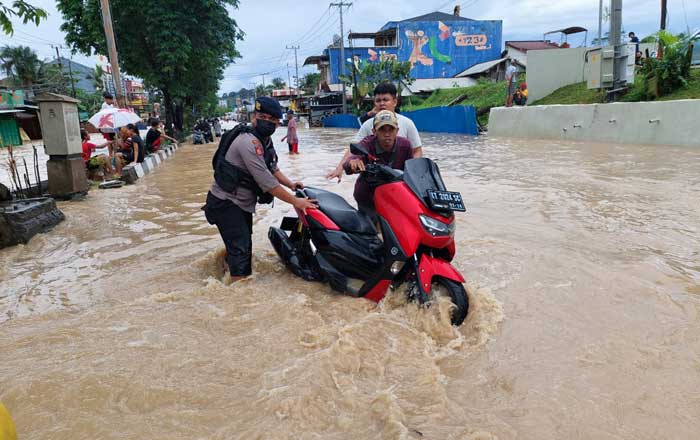 Seorang Anggota Polresta Samarinda yang diterjunkan membantu warga di lokasi banjir Kawasan Samarinda Utara. (foto : 1st)