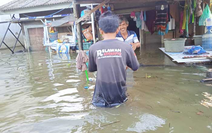Seorang relawan mengantarkan makanan siap santap kepada warga di Perumahan Bengkuring Jalan Terong 6 yang terendam banjir kemarin. (foto : 1st)